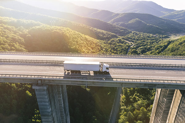 18 wheeler commercial truck crossing a very high bridge at sunrise