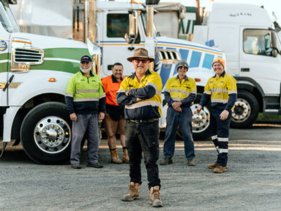 truckers standing in front of trucks smiling